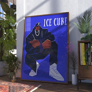 May include: A framed poster featuring a stylized illustration of Ice Cube in a squatting pose. The artwork has a blue background with the name "ICE CUBE" in white text at the top. The figure is wearing a black outfit and white sneakers.