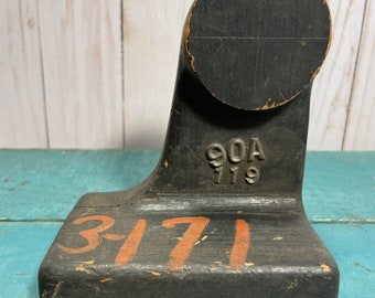 Peut inclure: Un dernier de chaussure en bois noir avec les chiffres "3-171" peints en orange sur la base et "90A 779" estampillés en noir sur le côté.
