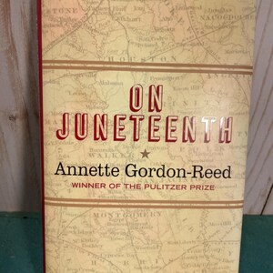 May include: A hardcover book titled On Juneteenth by Annette Gordon-Reed. The cover features a vintage-style map background in shades of tan and beige with red text. The title is printed in bold red letters, and the text Winner of the Pulitzer Prize is visible below the author's name.