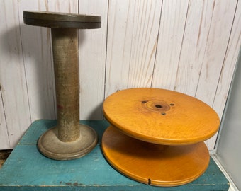 Peut inclure: Deux bobines en bois, l'une est une bobine haute et grise avec un dessus et un dessous ronds, l'autre est une bobine ronde et brun clair plus courte avec un dessus rond plus petit.