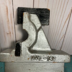 May include: A silver and black wooden tool with the text "WIL-14" on the bottom. The tool has a unique shape with a curved section and a flat top.
