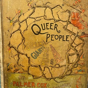 Op de afbeelding: Een vintage hardcover boek getiteld Queer People: Goblins, Giants, Merry-Men and Monarchs door Palmer Cox. De beige kaft bevat een centrale cirkelvormige illustratie van kale boomtakken omringd door diverse getekende figuren en een koning.