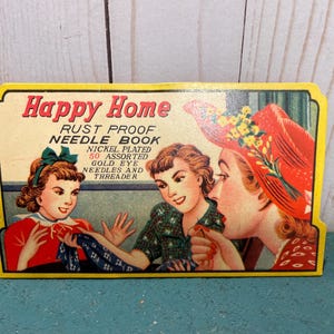 Könnte beinhalten: Vintage Happy Home Rostfreier Nadelbuch-Verpackung mit drei Frauen beim Nähen. Die Verpackung ist gelb mit roten und blauen Akzenten. Der Text auf der Verpackung lautet "Happy Home Rust Proof Needle Book Nickel Plated 50 Assorted Gold Eye Needles and Threader."