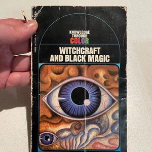 K&ouml;nnte beinhalten: Vintage Taschenbuch mit dem Titel "Witchcraft and Black Magic". Das Cover zeigt ein gro&szlig;es Auge mit blauer Iris und ein kleineres Auge darunter. Der Buchtitel ist wei&szlig;, mit "Knowledge Through Color" dar&uuml;ber.