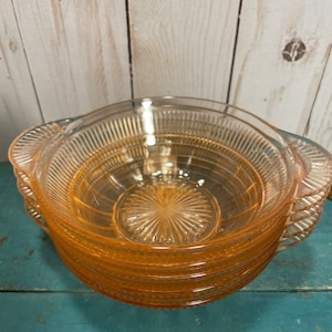 May include: A set of six vintage pink glass bowls with a fluted design and handles. The bowls are stacked on top of each other.