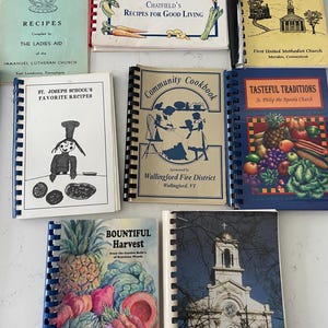 Könnte beinhalten: Eine Sammlung von zehn Kochbüchern mit bunten Umschlägen, die verschiedene Themen wie Kirchengemeinden, Schulrezepte und reiche Ernten zeigen. Die Kochbücher sind mit Spiralbindungen versehen und tragen Titel wie "Out of Our Kitchens", "Chatfield's Recipes for Good Living", "Community Cookbook", "Tasteful Traditions" und "Bountiful Harvest".