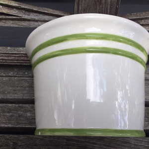 May include: White ceramic planter with green stripes around the top and bottom.
