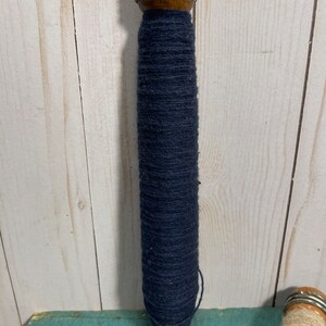 Peut inclure: Une bobine en bois avec un dessus en m&eacute;tal et une grande quantit&eacute; de fil bleu fonc&eacute; enroul&eacute; autour.
