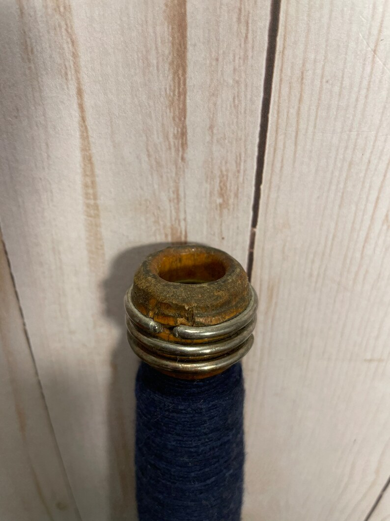 Peut inclure: Une bobine en bois avec un anneau m&eacute;tallique autour du haut, tenant un fil bleu fonc&eacute;.