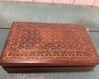 May include: A wooden box with a decorative inlay of a geometric pattern in gold. The box is closed and has a hinged lid.