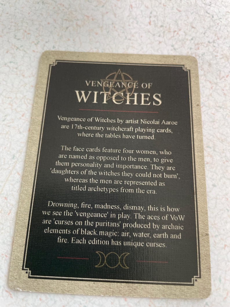 May include: A playing card from the "Vengeance of Witches" deck. The card has a dark background with the title "VENGEANCE OF WITCHES" in large, bold letters. The card's text describes the deck's theme of 17th-century witchcraft.
