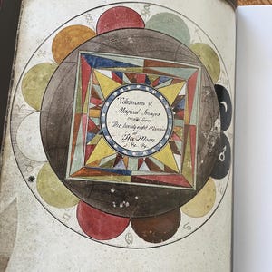 K&ouml;nnte beinhalten: Offene Buchseite mit einer detaillierten Illustration eines kreisf&ouml;rmigen Diagramms mit farbenfrohen geometrischen Formen, astrologischen Symbolen und Text. Das zentrale Design ist ein Quadrat in einem Kreis, mit dem Text "Talismans & Magical Images".