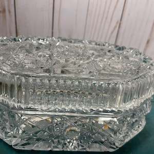 May include: A clear glass octagonal trinket box with a cut glass design. The box has a hinged lid and is perfect for storing small items.