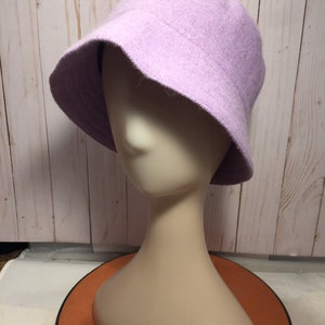 May include: A lavender bucket hat made of a soft, fuzzy material. The hat is on a white mannequin head.