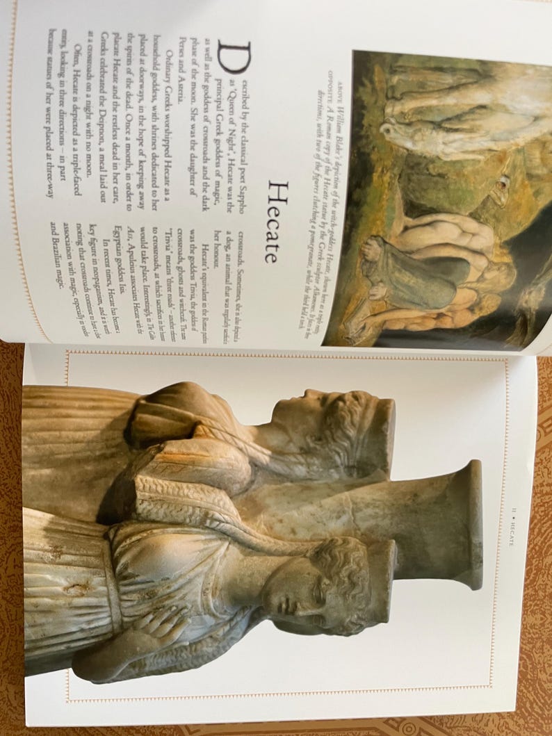 K&ouml;nnte beinhalten: Ein Foto einer Buchseite mit einer Skulptur der griechischen G&ouml;ttin Hekate. Die Skulptur, in hellem Beige, zeigt drei Figuren. Das Wort "Hekate" ist auf der Seite zu sehen.