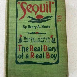 Puede incluir: Libro antiguo titulado "Sequil" de Henry A. Shute. La portada es verde con texto rojo y verde oscuro. El título "Sequil" está en una fuente estilizada. El libro también incluye el texto "The Real Diary of a Real Boy".