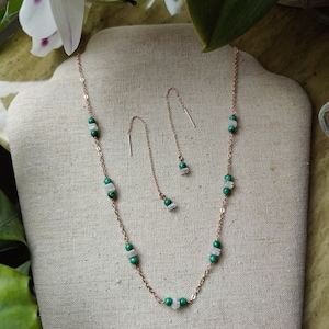 May include: A rose gold necklace and matching earrings with green and white gemstone beads.