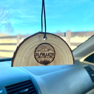 Peut inclure: Un diffuseur d'air de voiture en bois avec une finition en bois brun. Le diffuseur d'air a la forme d'un demi-cercle et est dot&eacute; d'une ficelle noire pour l'accrocher. Le diffuseur d'air pr&eacute;sente un motif de montagnes et d'arbres br&ucirc;l&eacute;s au bois avec le texte "SL PALLETS" au centre.