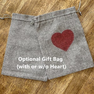 Peut inclure: Un sac cadeau en toile de jute gris avec un motif de c&oelig;ur rouge. Le sac a une fermeture &agrave; cordon et est &eacute;tiquet&eacute; "Sac cadeau facultatif (avec ou sans c&oelig;ur)".
