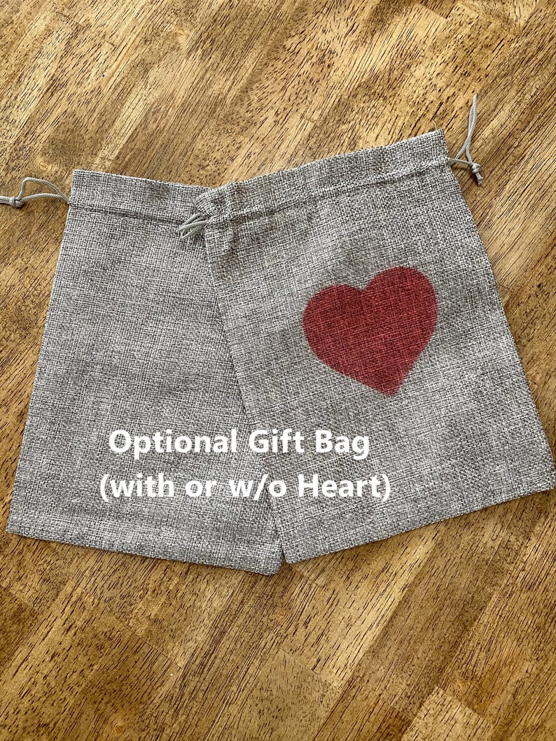 Peut inclure: Un sac cadeau en toile de jute gris avec un motif de c&oelig;ur rouge. Le sac a une fermeture &agrave; cordon et est &eacute;tiquet&eacute; "Sac cadeau facultatif (avec ou sans c&oelig;ur)".