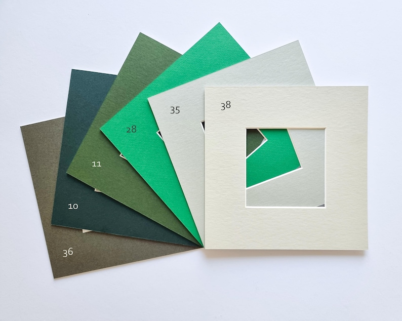 Puede incluir: Un abanico de seis paspart&uacute;s cuadrados de papel en varios tonos de verde y gris. Los paspart&uacute;s est&aacute;n etiquetados con los n&uacute;meros 36, 10, 11, 28, 35 y 38. Cada uno presenta un recorte cuadrado central que revela los colores de las capas.