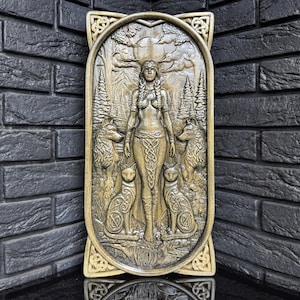 Può includere: Intaglio a rilievo dorato e dettagliato raffigurante una donna con lupi e gatti in un ambiente forestale. L'opera presenta intricati nodi celtici e una luna piena. Il rilievo è incorniciato con bordi decorativi.