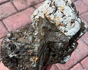 May include: A large, rough, gray and gold pyrite crystal cluster. The crystal has a metallic sheen and is composed of multiple, intergrown crystals.
