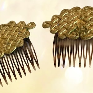 May include: Two gold hair combs with intricate Celtic knot designs. The combs have a brown plastic base with seven teeth.