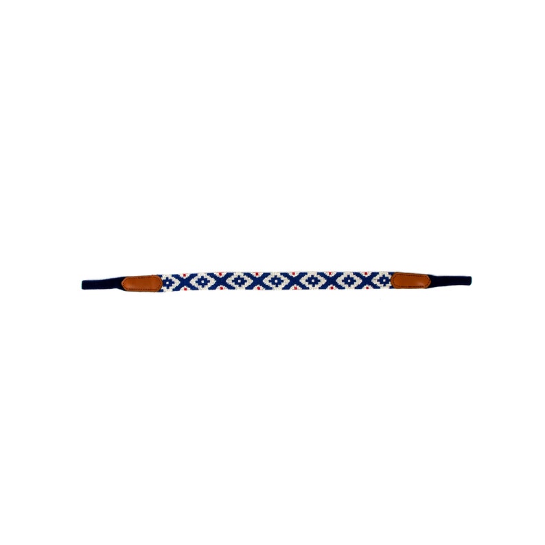May include: A white, blue, and red patterned camera strap with brown leather ends.
