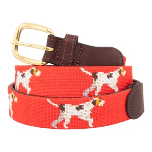 May include: A red woven belt with a brown leather buckle and a repeating pattern of white and brown dogs.