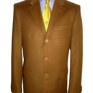 May include: A brown blazer with four buttons and a patch pocket. The blazer is worn over a light blue shirt with a white and light blue striped pattern and a yellow tie with a floral design.