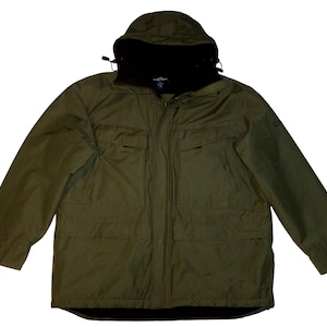 Op de afbeelding: Olijfgroene jas met capuchon en zwarte binnenvoering. De jas heeft een ritssluiting over de hele lengte, meerdere zakken en een capuchon met trekkoord. Ontworpen voor buiten, beschermt tegen de elementen.