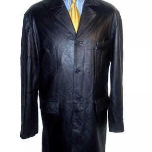 May include: A black leather long coat with a button closure and two pockets. The coat is on a mannequin wearing a blue and white striped shirt and a yellow tie.