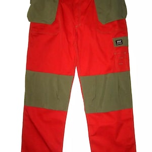 May include: Red and green work pants with multiple pockets. The pants have a green patch on the right leg with the text "HH" and "HELLY HANSEN".