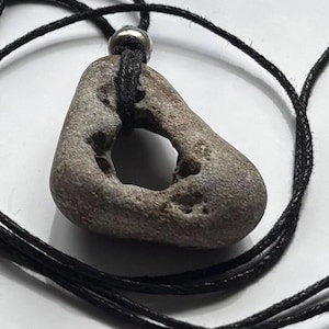 May include: A white ceramic mug with a black handle and the text "But First, Coffee" in a bold, black font. The mug is set against a blurred background, suggesting a cosy setting.