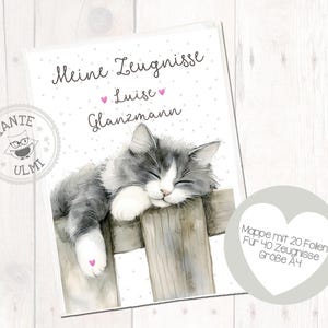 Puede incluir: Carpeta A4 con una ilustración en acuarela de un gato gris y blanco durmiendo sobre una valla de madera. El texto "Meine Zeugnisse Luise Glanzmann" está escrito encima del gato. Incluye un gráfico en forma de corazón.