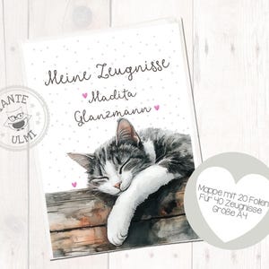 Puede incluir: Una tarjeta blanca con lunares rosas y el texto "Meine Zeugnisse Madita Glanzmann" con una ilustración de un gato durmiendo. La tarjeta está al lado de un círculo gris con el texto "Mappe mit 20 Follen Für 40 Zeugnisse Größe A4".