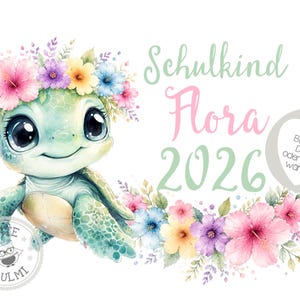 Puede incluir: Una ilustración en acuarela de una tortuga verde con una corona de flores rosas, moradas, amarillas y azules. El texto dice Schulkind Flora 2026. Un corazón gris contiene el texto Bügelbild DIN A5 oder DIN A4 wählbar y un logotipo circular dice Tante Ulmi.