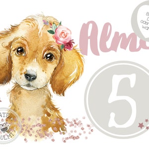 Op de afbeelding: Een aquarel-illustratie van een bruine puppy die een roze bloemenkrans draagt. De puppy zit op een achtergrond van roze glitter. De tekst "Alma" is geschreven in roze letters boven de puppy. Het nummer "5" is geschreven in wit op een grijze cirkel. De tekst "Bugebild DIN A5 oder DIN A4" is geschreven in zwart op een wit hart.