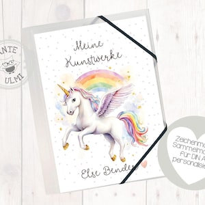 May include: A white unicorn with a rainbow mane and tail stands in front of a rainbow. The unicorn has wings and is surrounded by stars. The text "Meine Kunstwerke" is at the top of the image. The text "Else Bender" is at the bottom of the image. The text "Zeichenmappe Sammelmappe für DIN A4 personalisiert" is in a heart shape at the bottom right of the image.