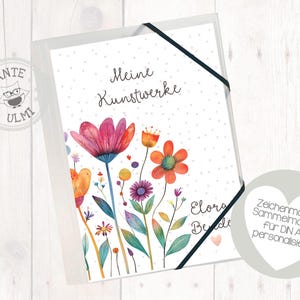 Könnte beinhalten: Ein weißer Ordner mit schwarzem Bandverschluss. Die Vorderseite des Ordners hat ein farbenfrohes Blumenmuster und den Text "Meine Kunstwerke". Die Rückseite des Ordners hat den Text "Zeichenmappe Sammelmappe für DIN A4 personalisiert".