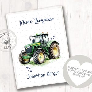 Op de afbeelding: Een witte map met een aquarel illustratie van een groene tractor. De tekst "Meine Zeugnisse" staat bovenaan, met "Jonathan Berger" onderaan. Een hartvormig label bevat tekst. Formaat A4.