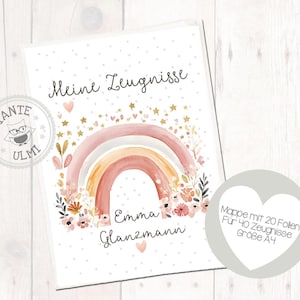 Może przedstawiać: Biała teczka z akwarelowym wzorem tęczy, kwiatowymi akcentami i imieniem "Emma Glanzmann". Tekst "Meine Zeugnisse" znajduje się na górze. Naklejka w kształcie serca wskazuje, że mieści 20 arkuszy na 40 świadectw, format A4.