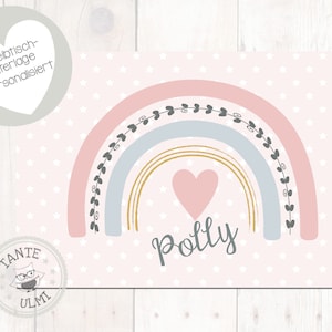Könnte beinhalten: Ein rosa-blauer Regenbogen mit goldenen Akzenten und einem rosa Herzen in der Mitte. Der Text "Polly" steht unter dem Herzen. Der Hintergrund ist hellrosa mit weißen Sternen.