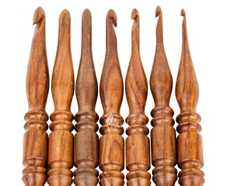 May include: Set of seven wooden crochet hooks with a brown finish. The hooks are arranged in a row, with the largest hook on the left and the smallest hook on the right.