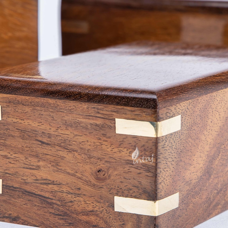 K&ouml;nnte beinhalten: Eine Holzkiste mit dunkelbrauner Oberfl&auml;che und goldenen Akzenten. Die Kiste hat eine glatte, polierte Oberfl&auml;che und ist aus hochwertigem Holz gefertigt.