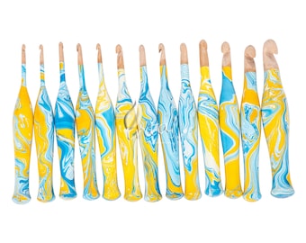 May include: A set of 14 colourful crochet hooks with a marbled blue and yellow design. The hooks are made of wood and have a smooth finish.