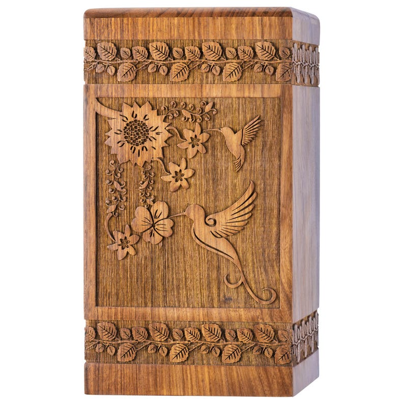 Front view of a polished Rosewood cremation urn featuring a detailed hummingbird feeding from vibrant pink and yellow flowers. The natural, rich grain of the wood is visible. Handmade wooden memorial box offering a beautiful nature-inspired resting place for ashes. Square shape with smooth finish.