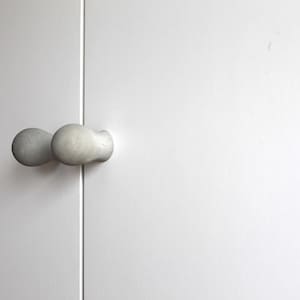 May include: A pair of white, round door knobs with a textured surface.