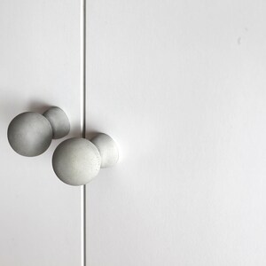 May include: Three round, gray, concrete cabinet knobs.